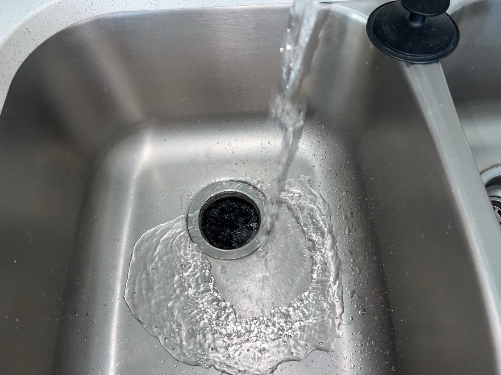 A kitchen sink with the faucet running